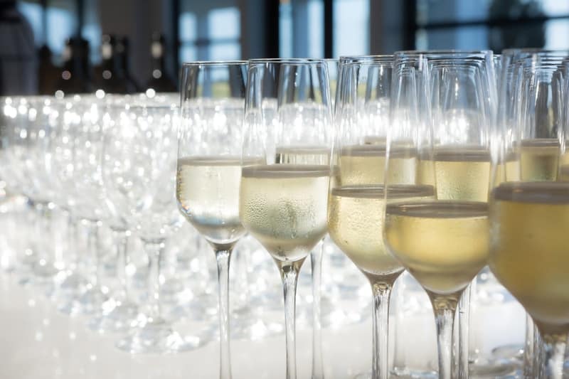 Rows of filled champagne flutes lined up on a white bar before the toast