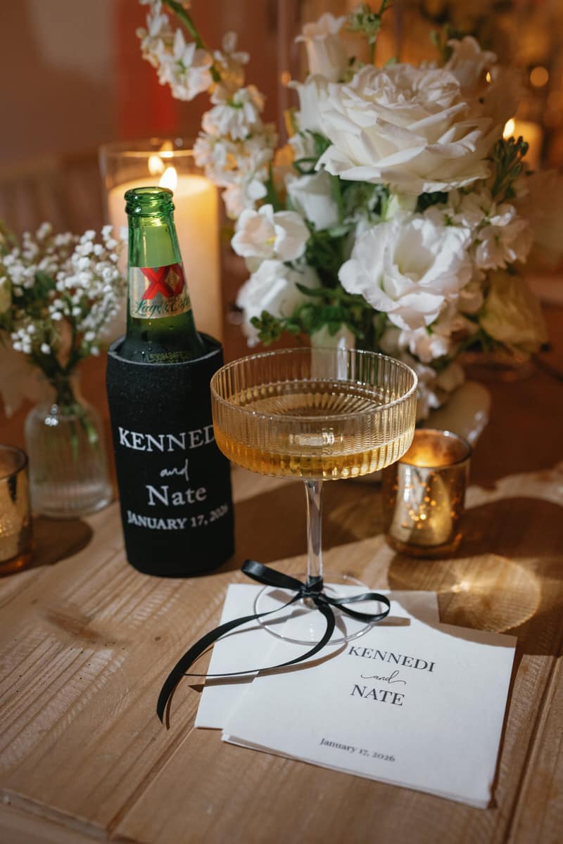 Reception place setting with a personalized koozie and gold champagne coupes