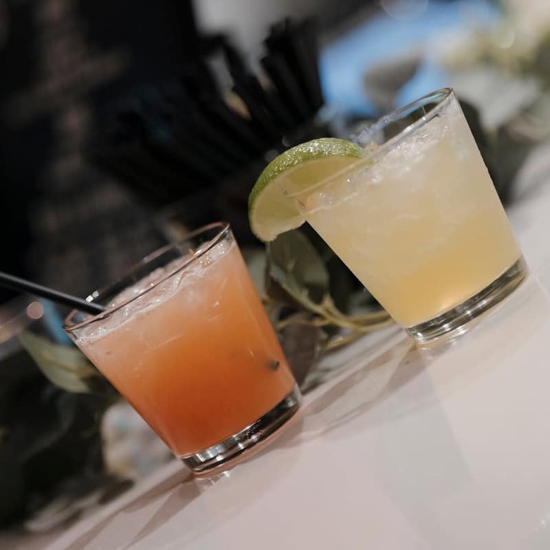 Two margaritas with salted rims and lime wheels waiting on the bar